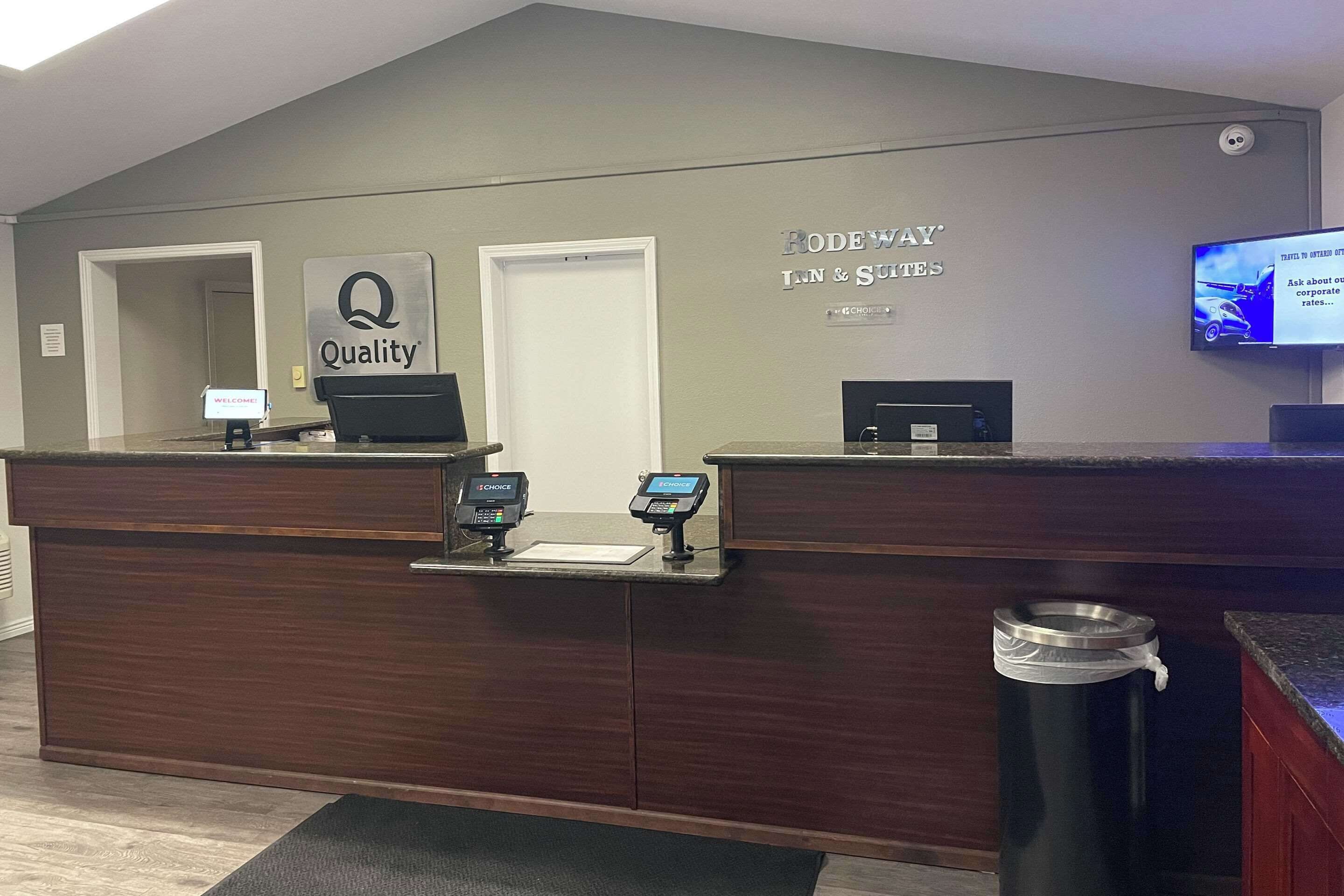 Un mostrador de recepción con un cartel que dice "Quality" y "Rodeway Inn & Suites".
