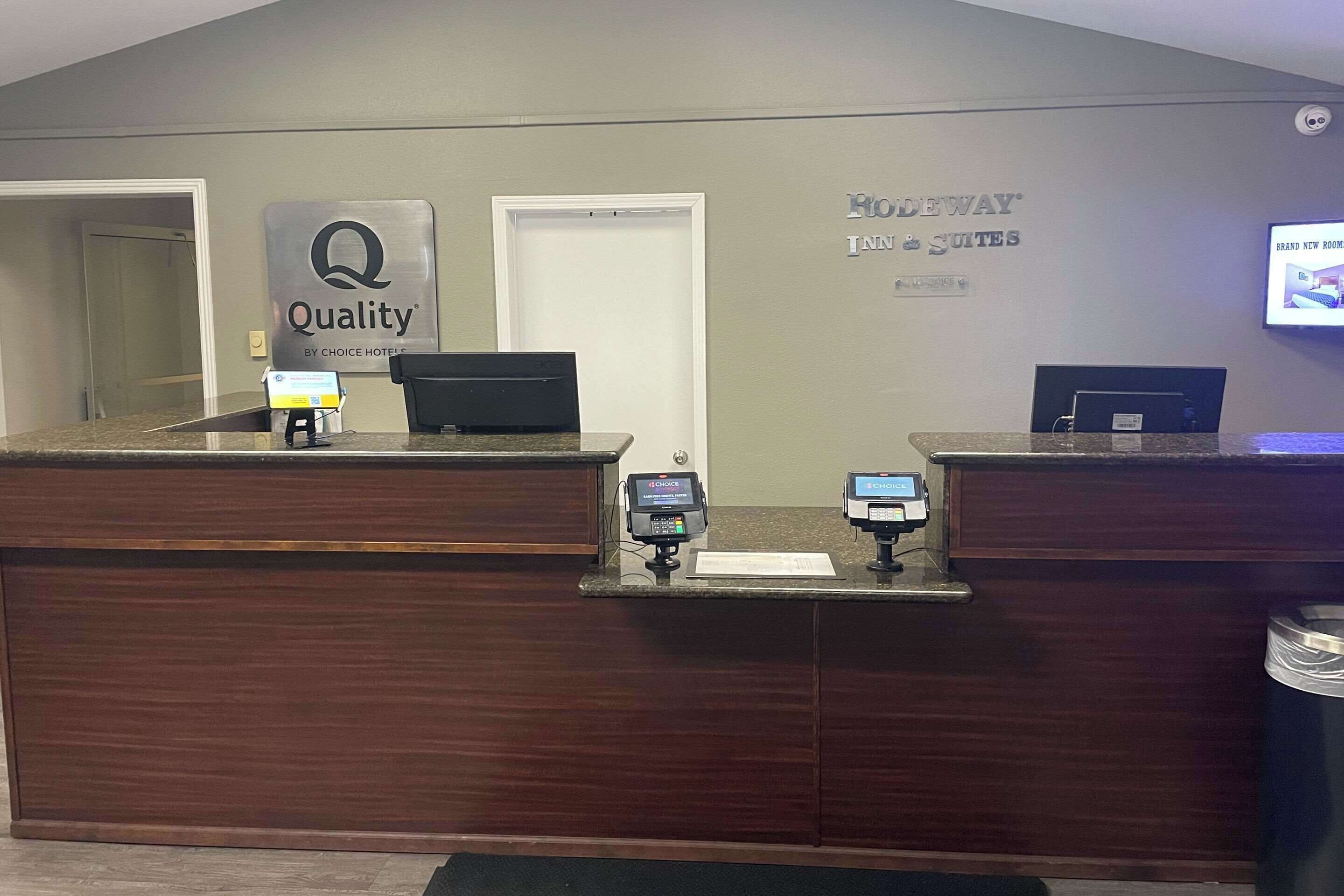 A hotel reception desk with a 'Quality' sign, a digital display, and a 'Rio de Janeiro' sign.