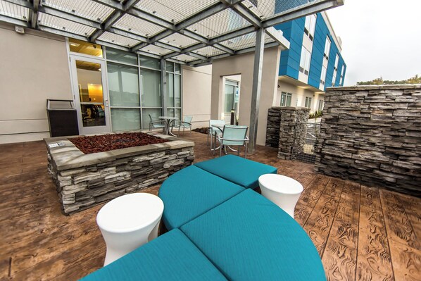 Relax in this serene outdoor seating area with a stone bench, two round tables, and a sheltered roof structure.