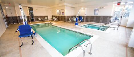 A hotel swimming pool with two separate sections, a lifeguard chair, and a chair with a backrest.