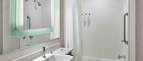 Une salle de bain moderne avec une douche à parois de verre, un lavabo blanc et une baignoire.
