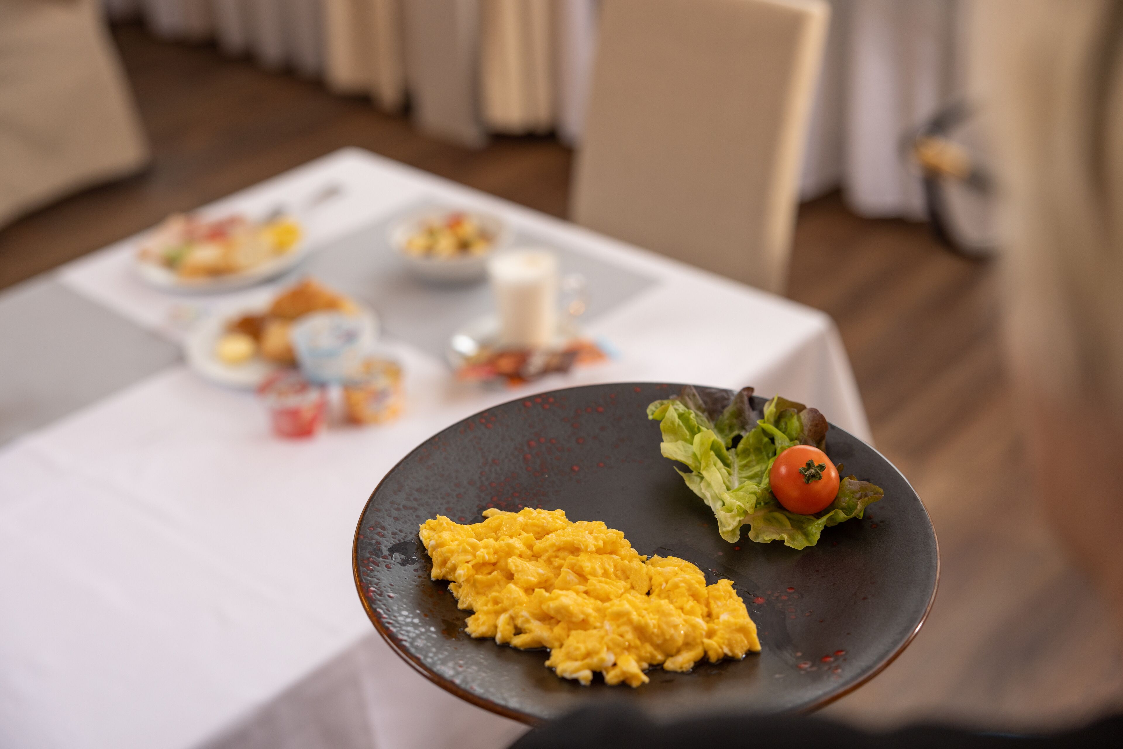 A dining table with a plate of scrambled eggs and a side salad.