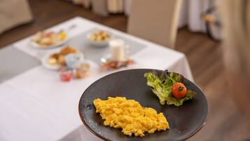 A dining table with a plate of scrambled eggs and a side salad.