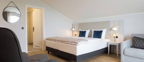 Une chambre à coucher moderne avec un lit, deux tables de chevet, une chaise et un miroir au mur.