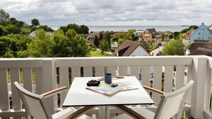 A balcony with a table, chairs, and a map. - Koopmanns Hotel und Lädchen (Göhren)