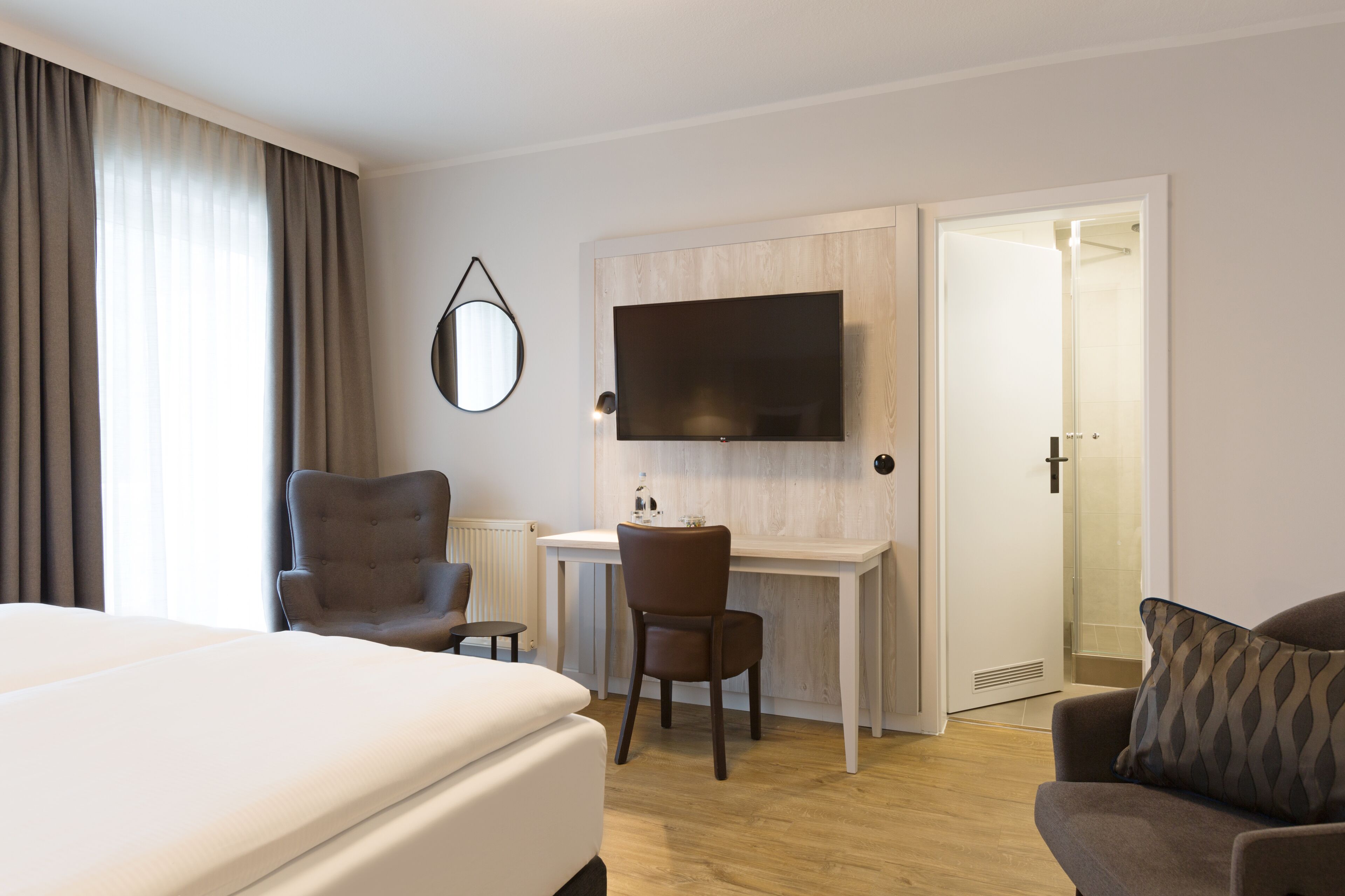 Een hotelkamer met een bed, een bureau met stoel, een televisie en een deur naar een badkamer.