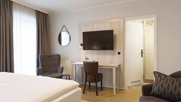 Een hotelkamer met een bed, een bureau met stoel, een televisie en een deur naar een badkamer.