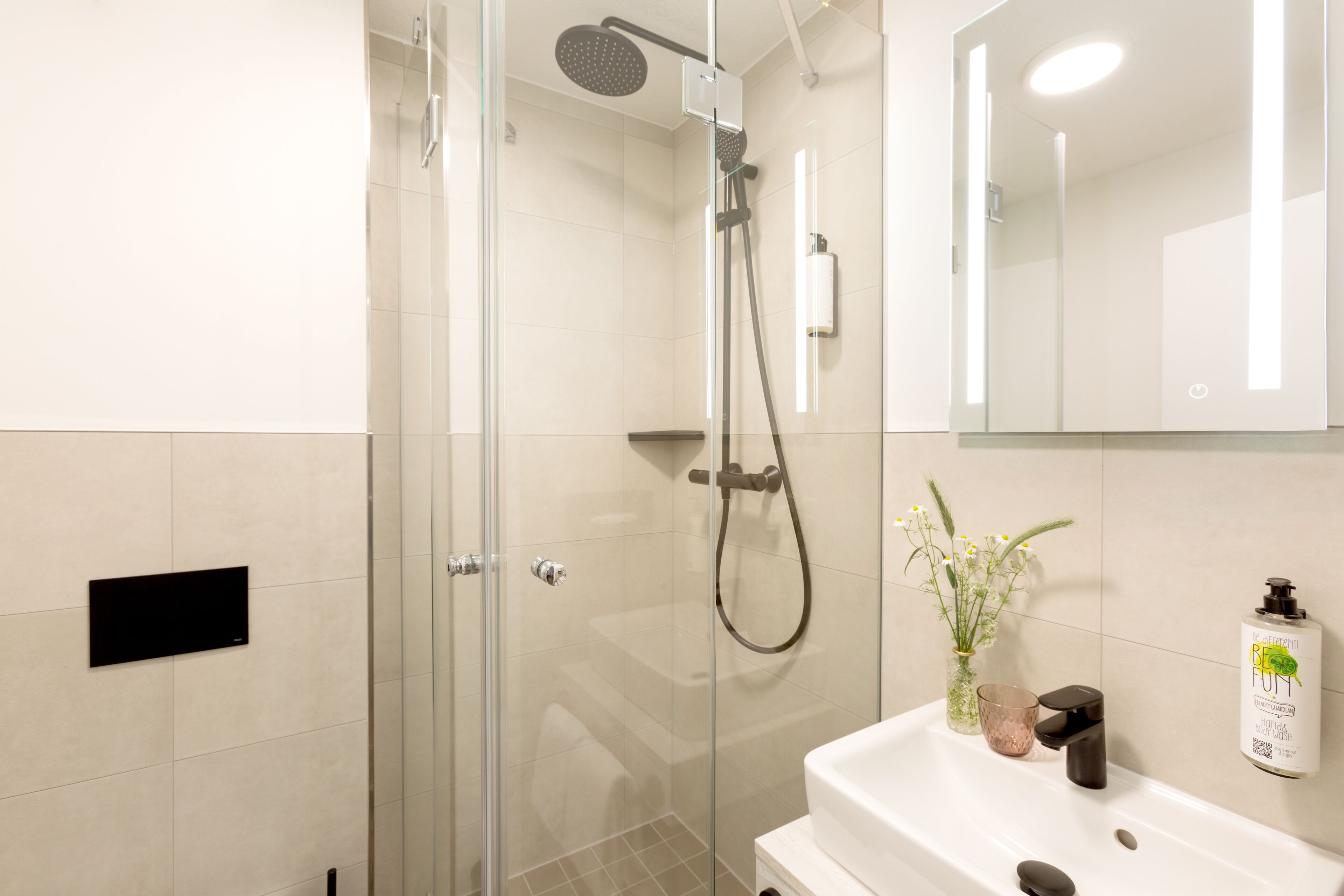 Un baño moderno con cabina de ducha de vidrio, lavabo blanco y espejo.