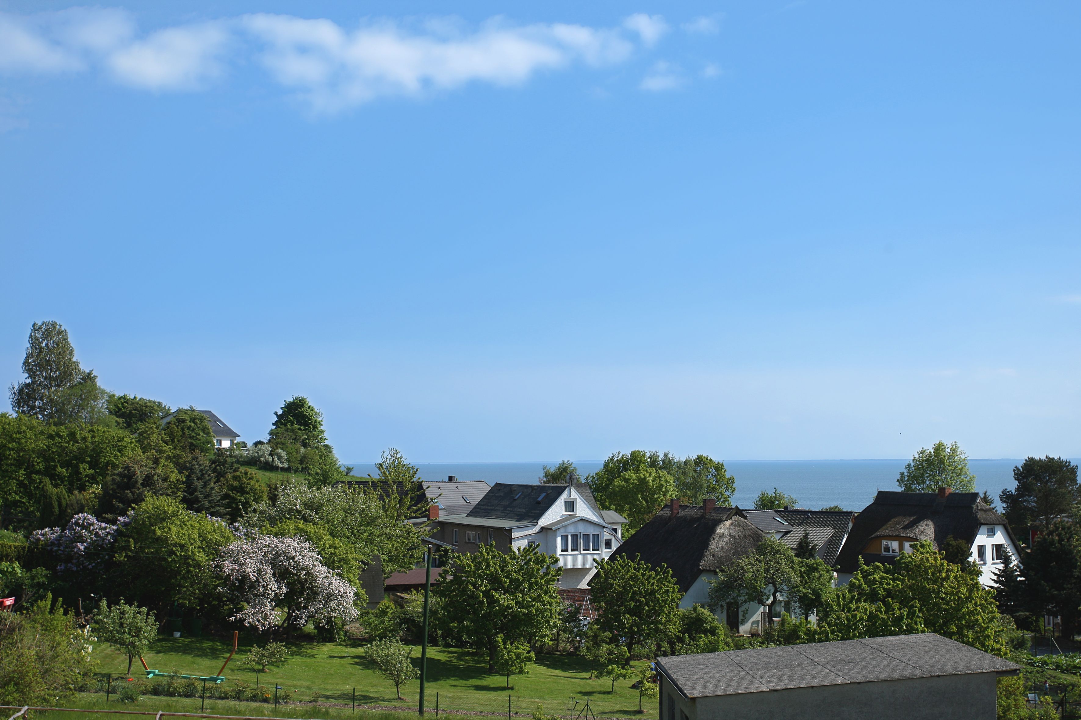 Een woonwijk met huizen, een grasveld en uitzicht op zee.