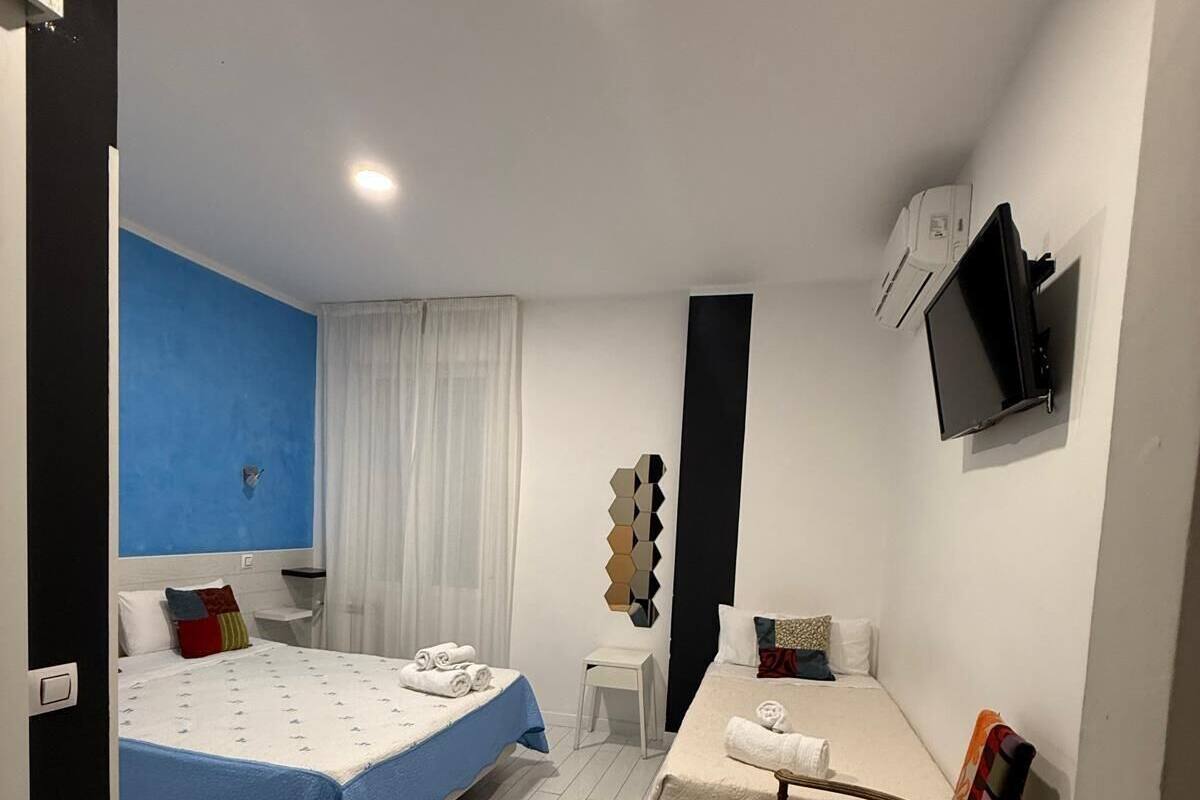 Habitación de hotel con cama, escritorio, silla, televisor y una mesita.