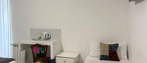 Une chambre d’hôtel équipée d’un lit, d’un bureau, d’une chaise, d’une petite table de chevet et d’un téléviseur fixé au mur.