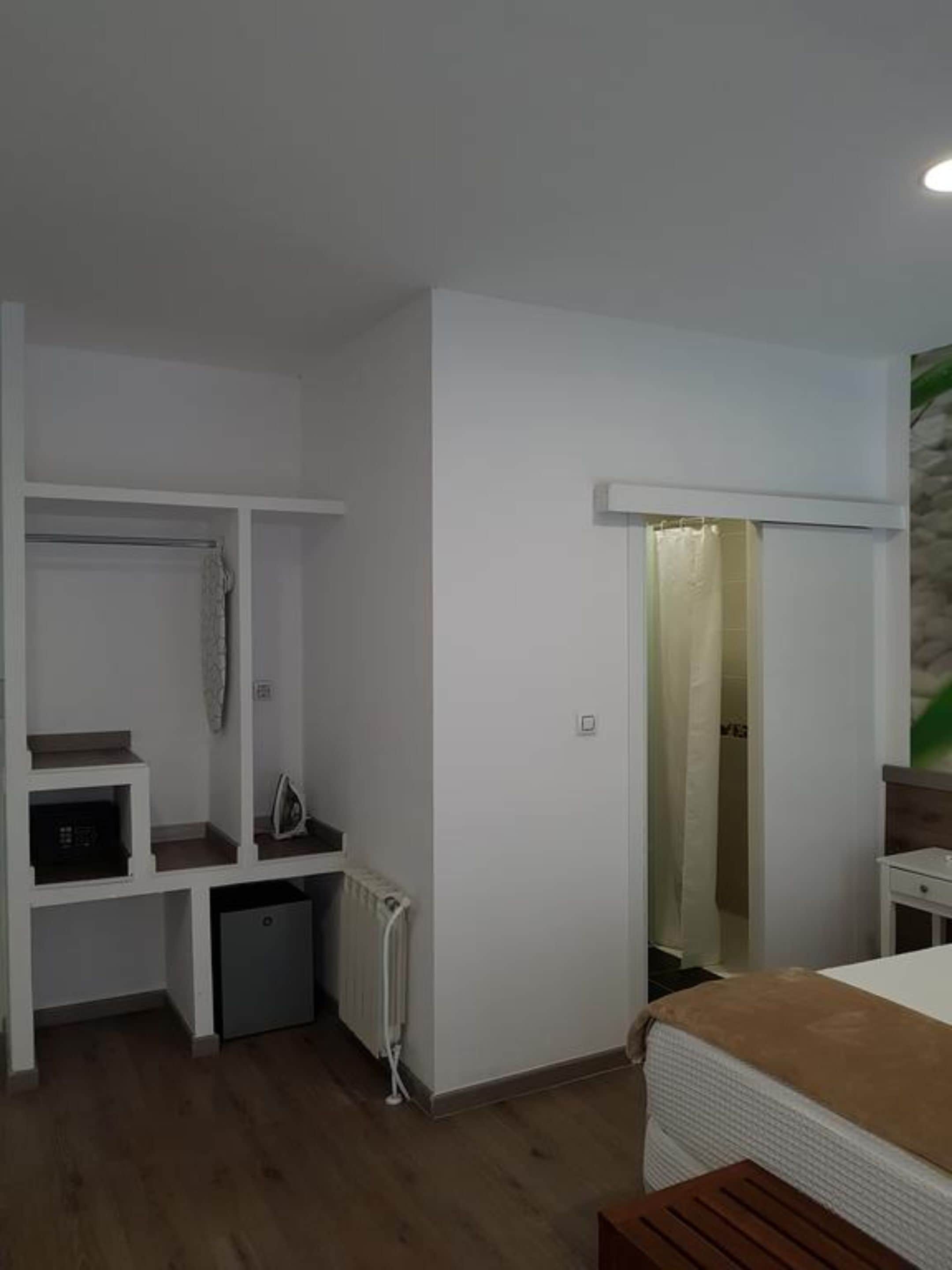 A bedroom with a bed, a desk, a radiator, and a wardrobe.