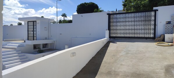 A modern residential area with a white building, a black gate, and a concrete pathway. - Villa Ambre (La Marsa)