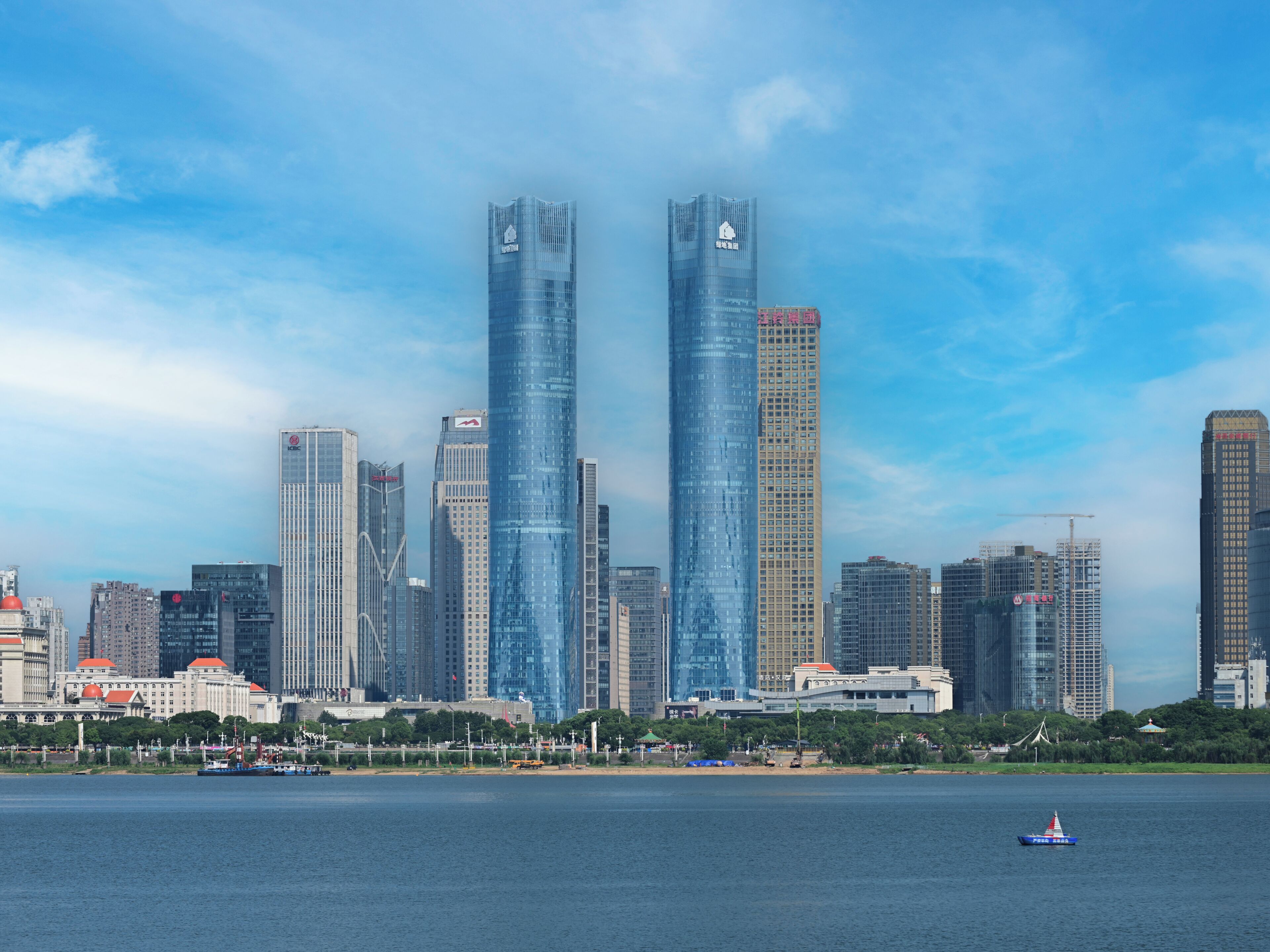 A city skyline with modern skyscrapers, a body of water in the foreground, and a small boat.