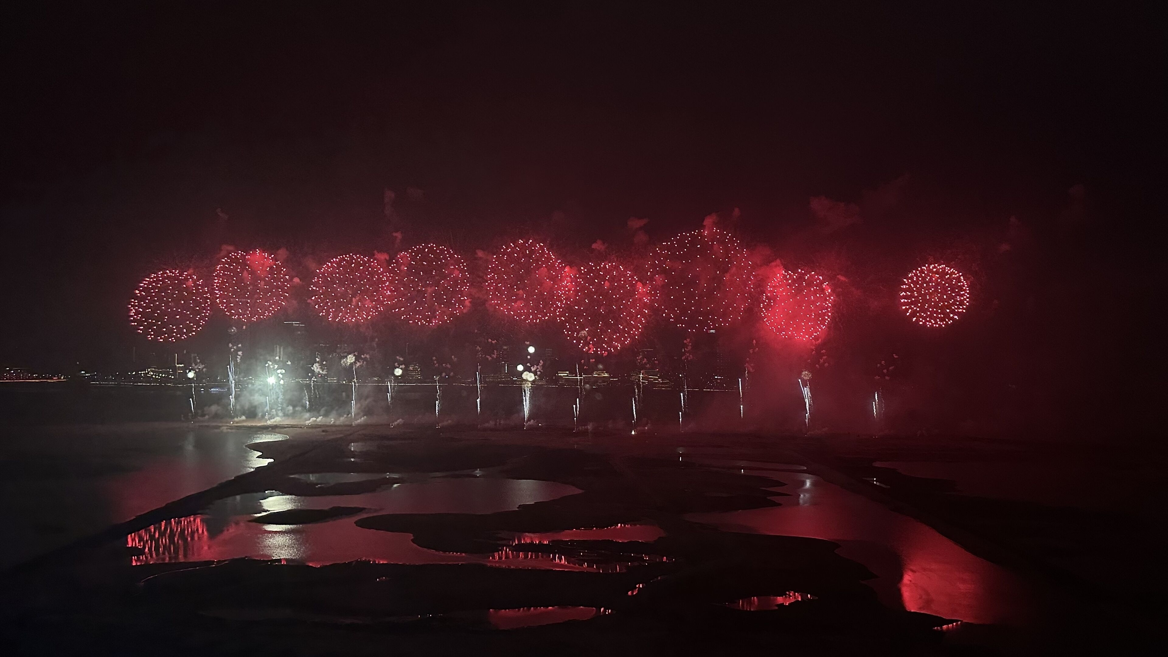 A nighttime scene with fireworks over a body of water.