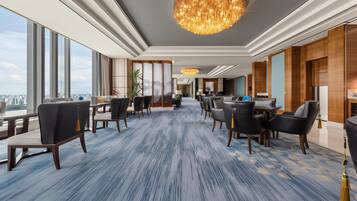 Un moderno vestíbulo de hotel con una alfombra de estampado azul, amplias ventanas que ofrecen vistas a la ciudad y una araña.