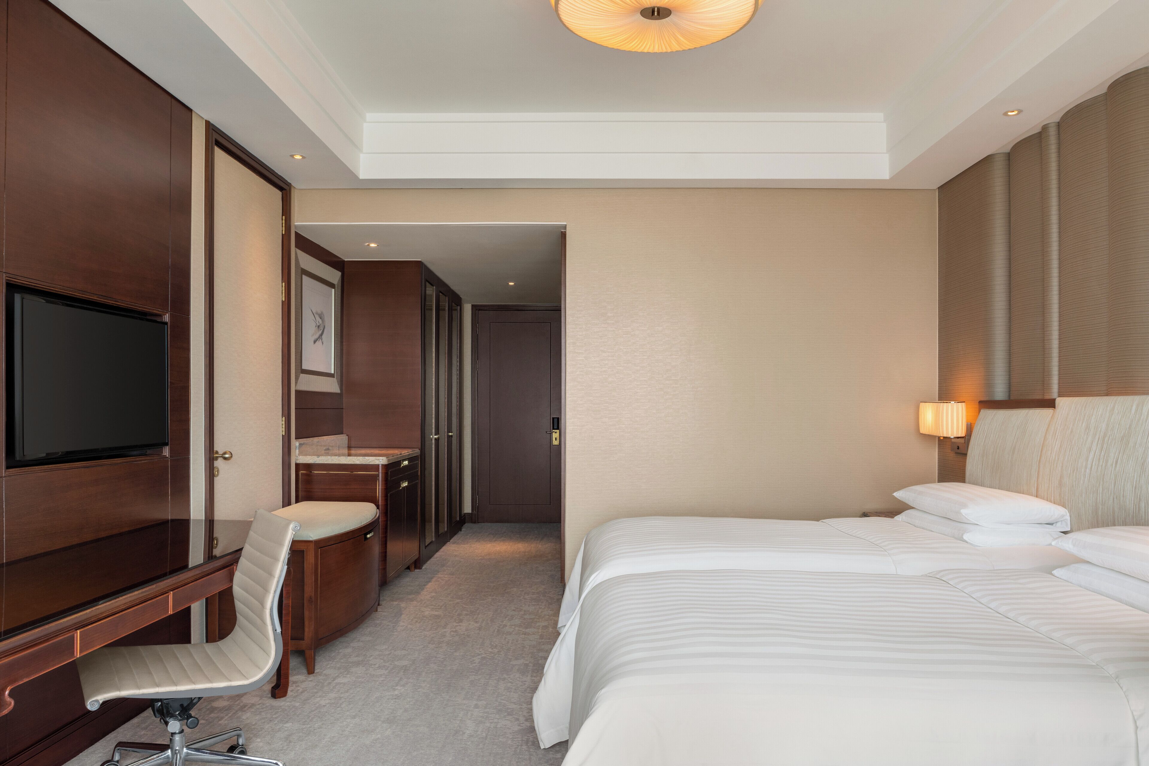 Una habitación de hotel con una cama grande, un escritorio con silla, un televisor y una lámpara.
