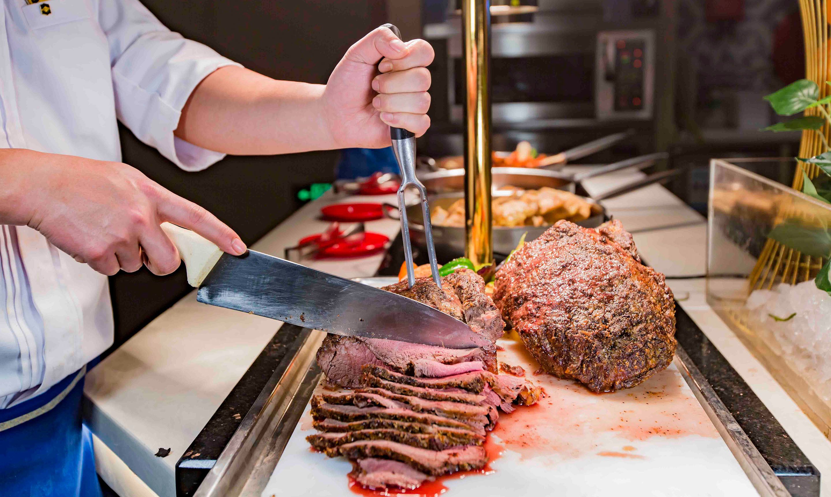 Un chef cortando carne en una tabla de cortar.