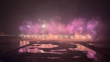A nighttime fireworks display over a body of water with reflections.