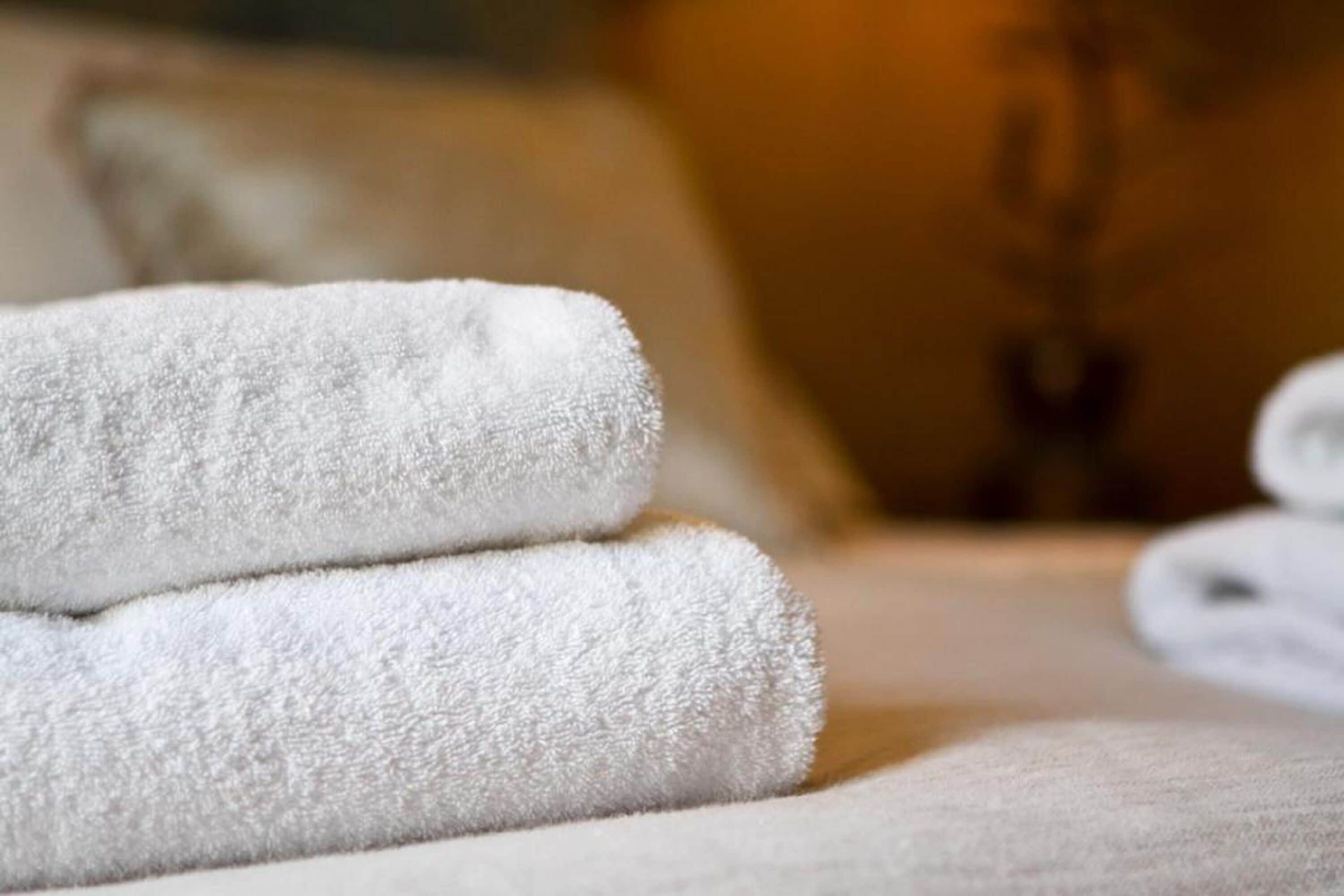 A stack of white towels on a bed.