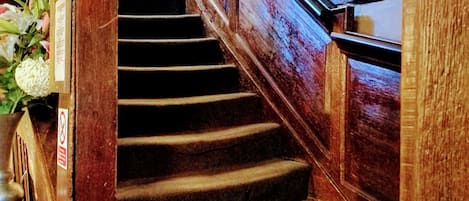 A wooden staircase with a handrail, leading to an upper floor.