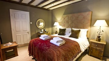 Un dormitorio con una cama grande, dos mesitas de noche, un tocador, una puerta y un espejo.