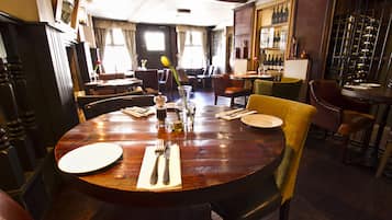 Un restaurant avec une table à manger en bois, dressée pour deux personnes, entourée de chaises.