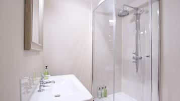 A bathroom with a white sink, mirror, and glass-enclosed shower.