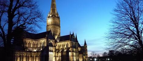 A historic church with a tall spire and illuminated windows.