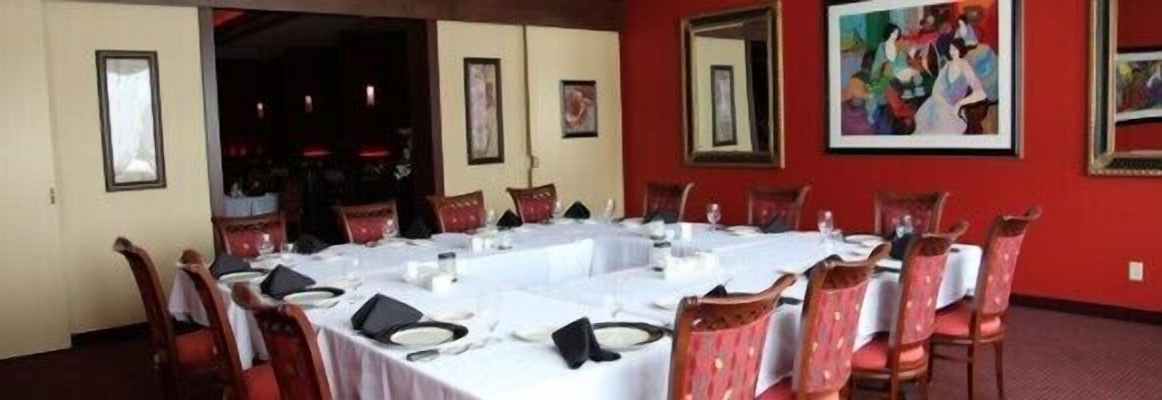 Un comedor con una mesa larga dispuesta para una comida, rodeada de sillas.