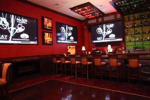 Un espace bar dot é de plusieurs écrans diffusant des publicités, de tabourets de bar et d’un comptoir bien garni.