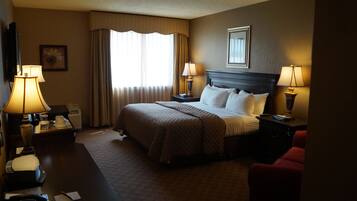 A hotel room with a large bed, two bedside tables with lamps, a desk with a telephone, and a chair.