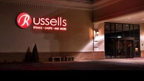 Een gebouw met een grote, verlichte reclamebord waarop staat: "Russells STEAKS - CHOPS - AND MORE".