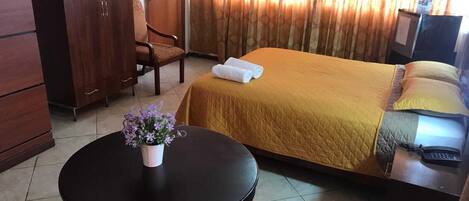 Habitación de hotel con cama, escritorio, silla, una mesita con un florero y teléfono.