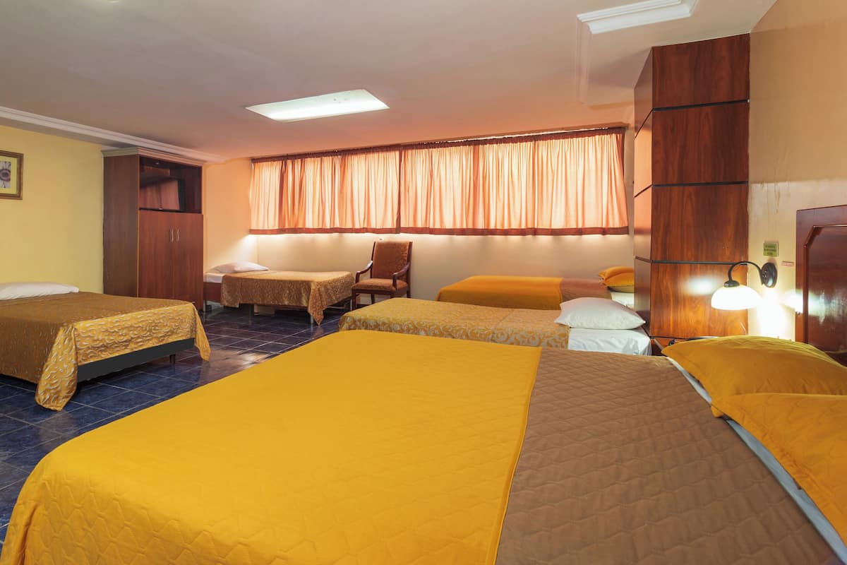 Une chambre d’hôtel avec trois lits, une armoire en bois, un bureau et une chaise.