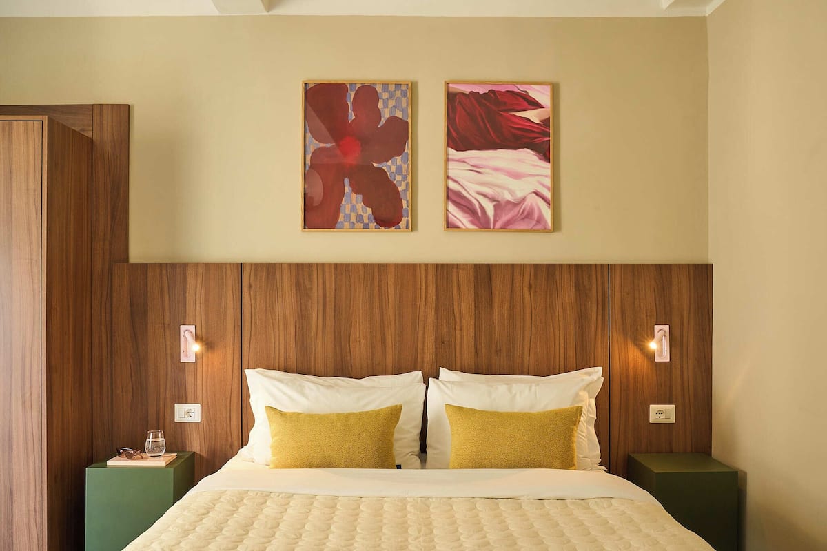 A neatly arranged hotel room with a large bed, two side tables, and two wall-mounted light fixtures.