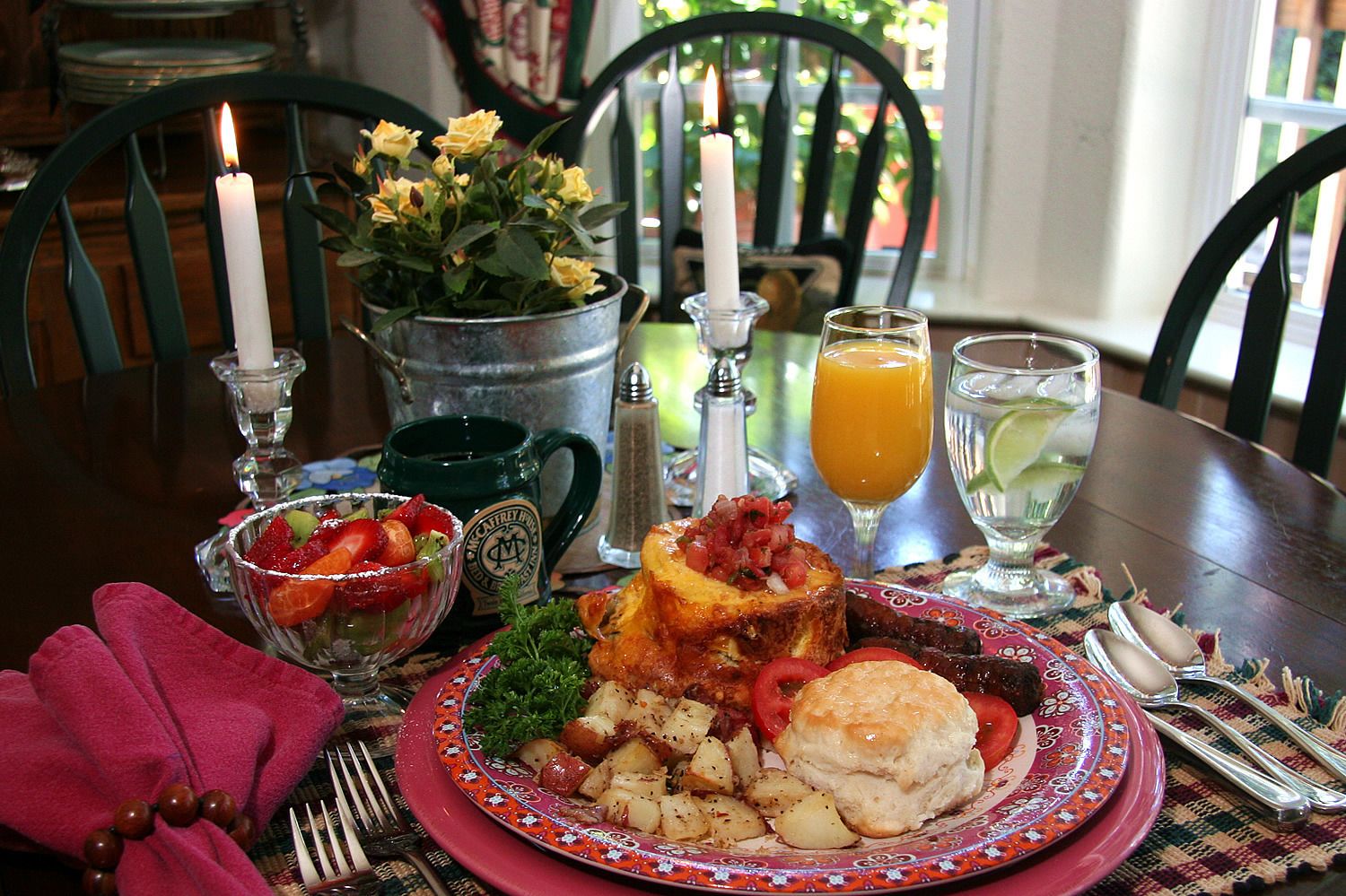 A breakfast setting with a plate of food, a mug, a candle, and a glass of orange juice.