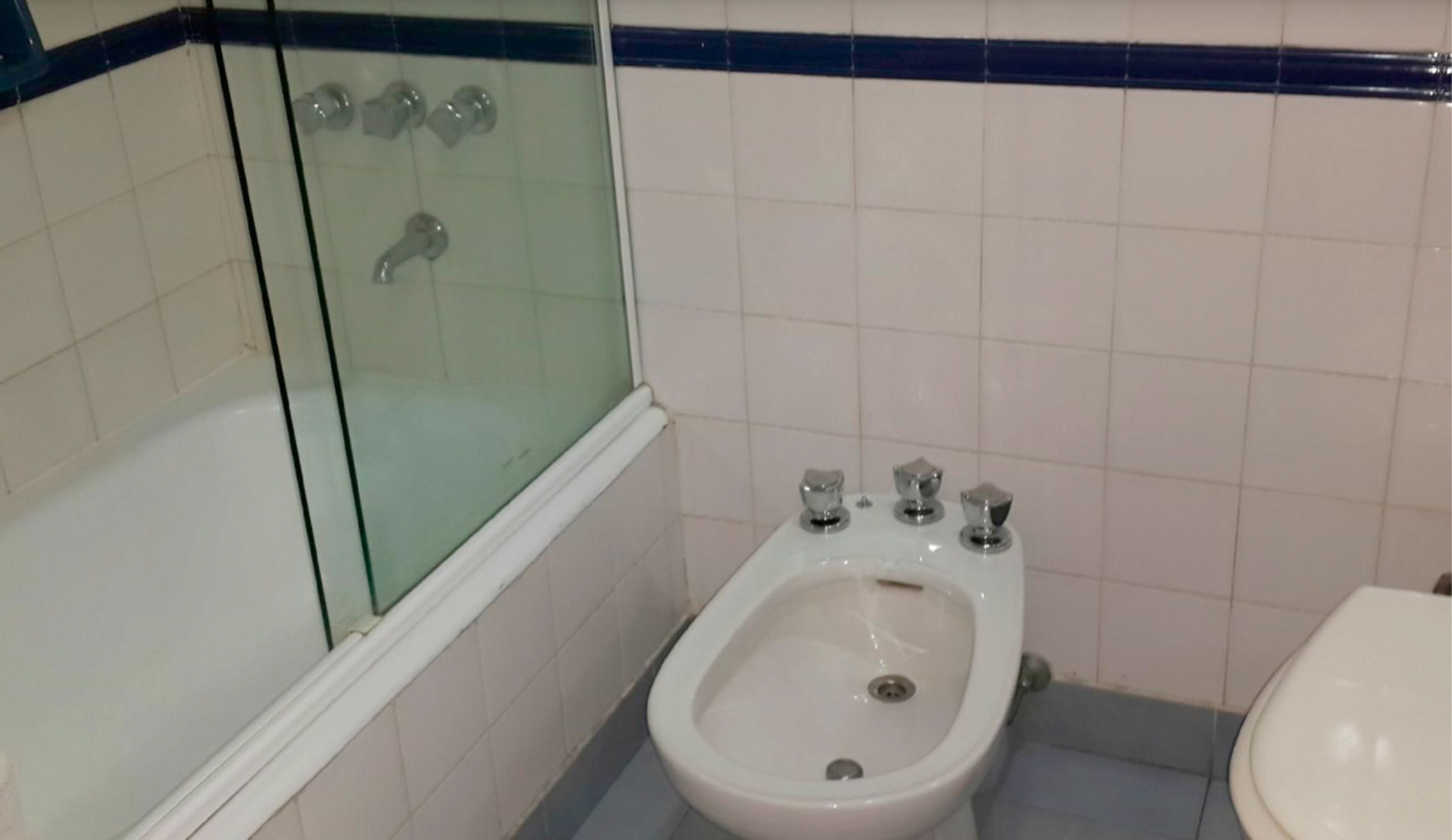 Un baño con ducha de vidrio, un bidé y un inodoro.