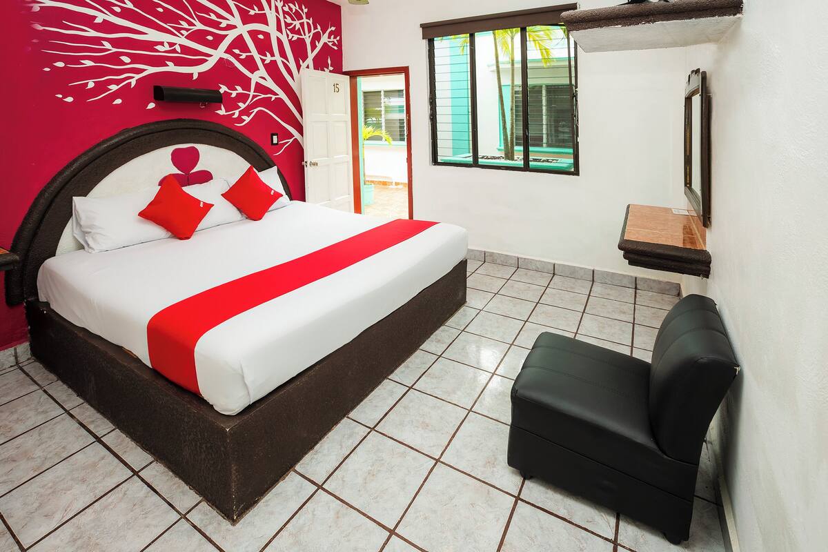 Un dormitorio con una cama, una silla, una ventana y una puerta.