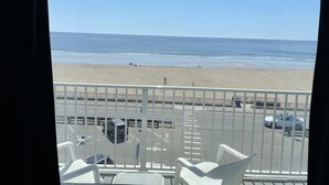 A view from a balcony overlooking a beach with a parking area in the foreground. - Hampton House Hotel (Hampton)