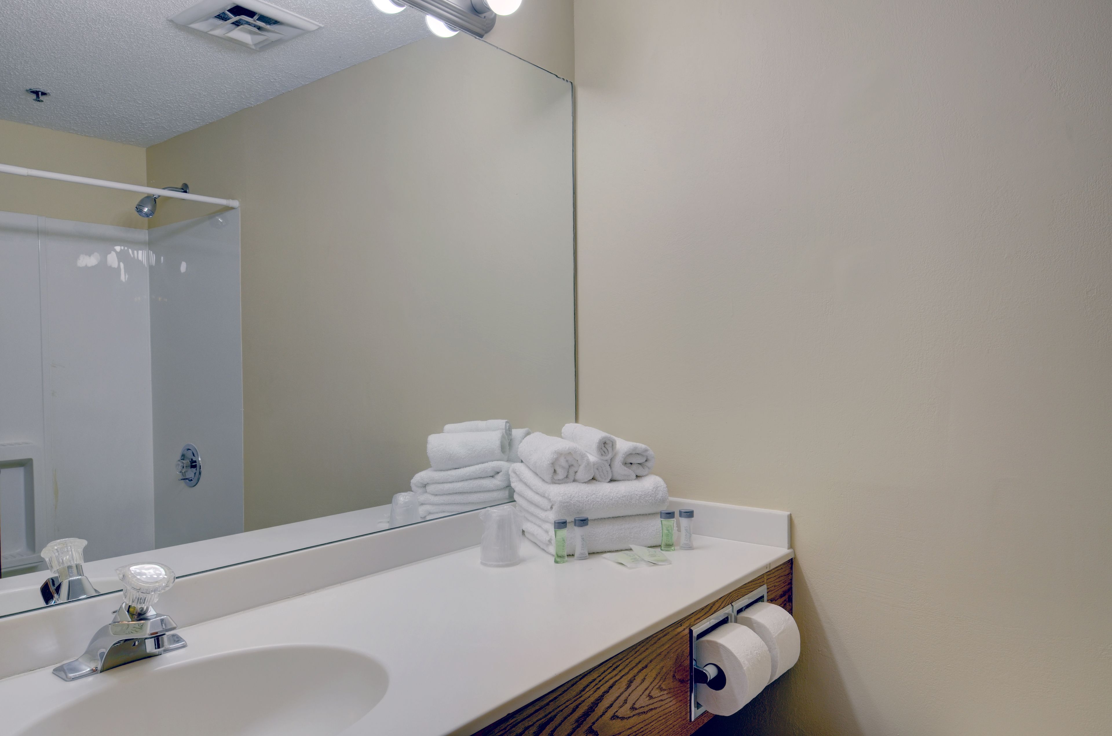 Une salle de bain avec un lavabo blanc, un miroir, un porte-serviettes et un support à papier toilette.