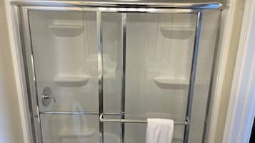 A glass-enclosed shower with a chrome frame, a white towel hanging on the door, and a chrome showerhead.