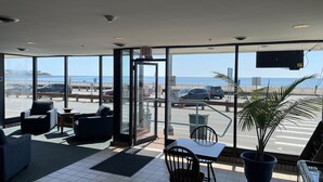 A hotel lobby with a view of the beach and parking area. - Hampton House Hotel (Hampton)