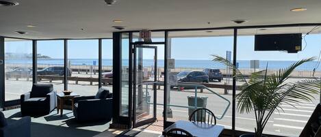 A hotel lobby with a view of the beach and parking area.