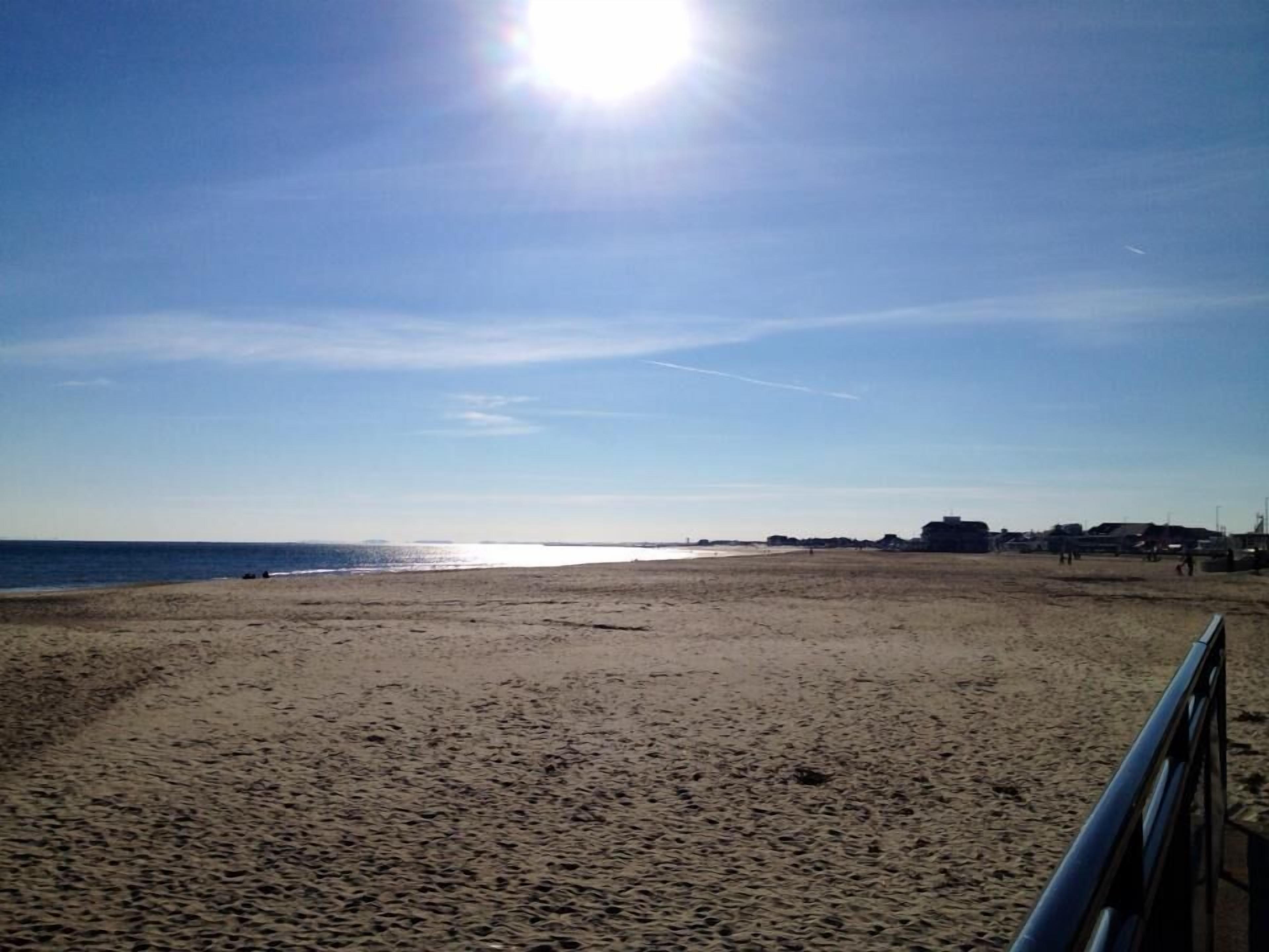 A beach with a clear sky and the sun shining.