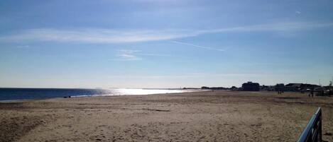 A beach with a clear sky and the sun shining.
