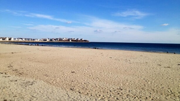 A wide sandy beach with a clear blue sky and a distant shoreline with buildings. - Hampton House Hotel (Hampton)