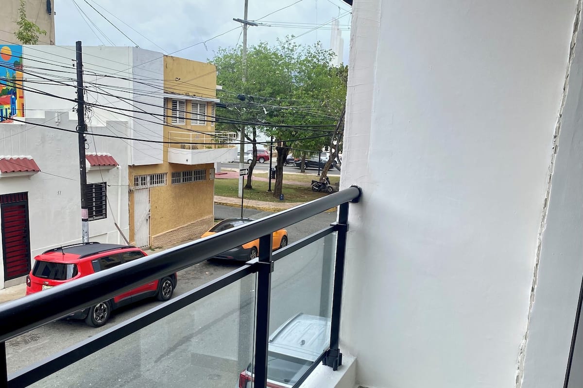 A balcony with a view of a street, a tiled floor, and a railing.