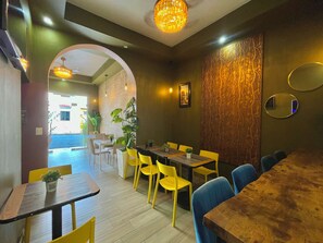 A restaurant interior with multiple tables and chairs, a chandelier, and a view of the street outside.