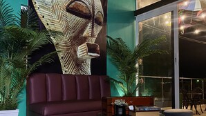 Et moderne interiør med et stort muralmaleri, en blød rød sofa og et rundt bord med et ur.